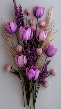 a bunch of purple flowers sitting on top of a white table next to dry grass