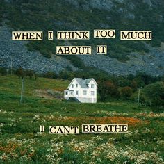 a white house sitting on top of a lush green field next to a mountain covered in flowers