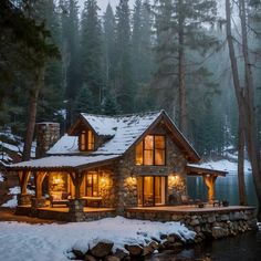 a log cabin is lit up at night by the water's edge with snow on the ground