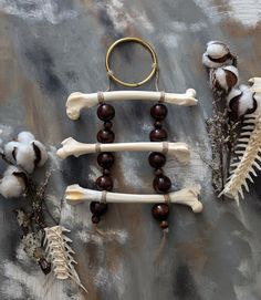 three bone and wood bead necklaces are displayed on a table with dried flowers