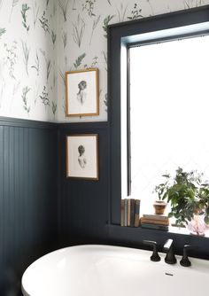 a white sink sitting under a window next to a potted plant in a bathroom