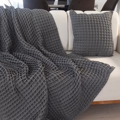 a couch with two pillows on top of it and a blanket draped over the back