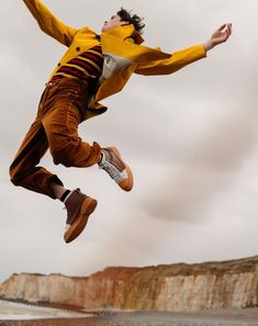 a man is jumping in the air with his feet up and one foot on his hip