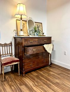 an old dresser with a mirror on top and a chair in the corner next to it