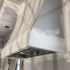 a white stove top oven sitting inside of a kitchen next to a wall mounted exhaust fan