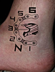 a tattoo on the foot of a person with a bike chain around their ankles and words written in black ink