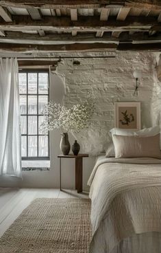 a bedroom with brick walls and white bedding, vases on the side table