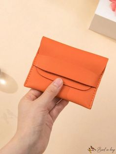 a hand holding an orange leather wallet