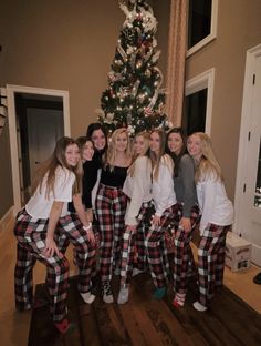 a group of girls standing in front of a christmas tree