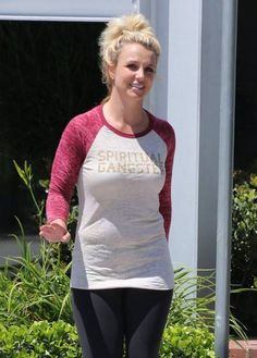 a woman with blonde hair wearing a white and pink shirt is walking down the street