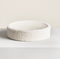 a white dog bed sitting on top of a white table next to a black cat