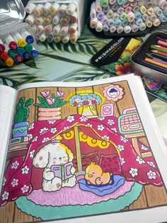 an open coloring book sitting on top of a table filled with markers and crayons