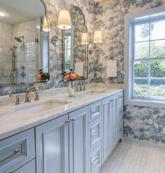 a large bathroom with two sinks, mirrors and lights on the side of the wall