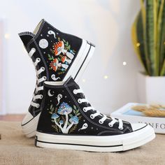 "Black Converse High Top shoes embroidered with mushroom garden and ghosts. With many years of shoe embroidery experience, this time I was really happy to receive a personalized canvas sneaker embroidery design for a very special customer. They sent me pictures of mushrooms in their favorite colors and they wanted me to combine it with ghosts. I found this request interesting and this was the gift they wanted to send to their loved ones. I also love this custom embroidery style. If you also need a pair of hand-embroidered Converse Shoes as a gift of the highest quality or a pair of hand-embroidered Vans Shoes, please message me. I will design and embroider a special pair of shoes. * The detail information of product: '' Custom Converse Chuck Taylor 1970s Embroidered Ghosts and Mushrooms Sn Converse Color Mouse, Vans High Top Sneaker Custom, Sneaker Embroidery, Embroidered Mushrooms, 1970s Shoes, Embroidered Vans