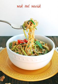 a fork is lifting up some noodles from a bowl