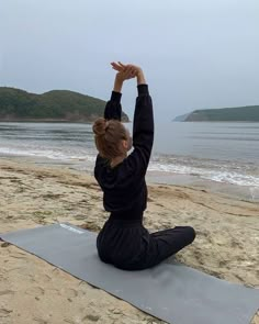 a woman is doing yoga on the beach