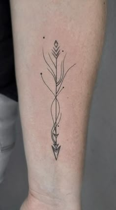 an arrow tattoo on the back of a woman's left leg, which is black and white