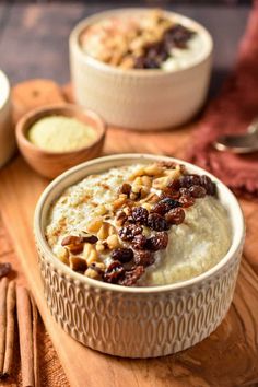 two bowls filled with food sitting on top of a wooden table next to spoons