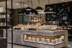 a buffet with lots of plates and bowls on the counter in front of black chalkboard