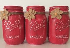 three red mason jars decorated with burlocks and flowers