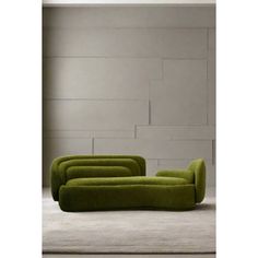 a green couch sitting on top of a white floor next to a wall in an empty room