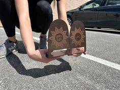 a person kneeling down on the ground holding two pieces of paper with sun designs on them