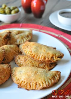 several pastries on a white plate with tomatoes and olives in the back ground