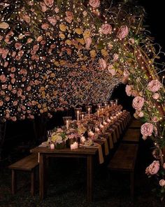 a long table with candles and flowers on it is lit up at night by the lights