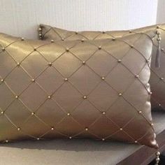 two gold pillows sitting on top of a bench