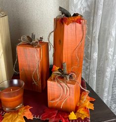 three wooden blocks with fall leaves on them, one has a candle and the other two are wrapped in twine