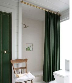 a white toilet sitting next to a green door in a bathroom with a wooden chair