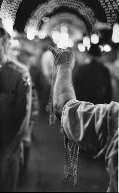 an old photo of a person holding something in their hand with other people standing around