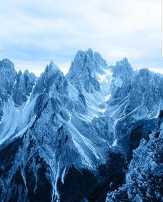 the mountains are covered in snow and blue hued clouds, with no one visible on them