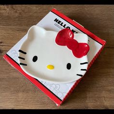 a hello kitty plate sitting on top of a wooden table next to a package of candy