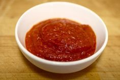 a white bowl filled with sauce on top of a wooden table