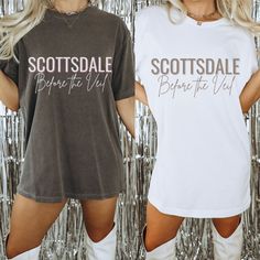 two women standing next to each other in front of silver tinsel wall wearing t - shirts that say scottsdale before the veil