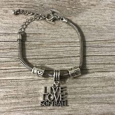 a bracelet that says live love softball on the front and back of it, with a charm