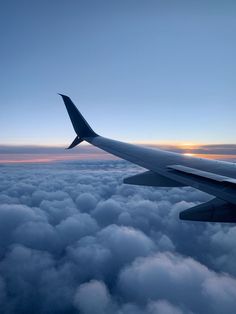 an airplane wing above the clouds at sunset