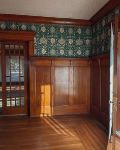 an empty room with wood paneling and green wallpaper