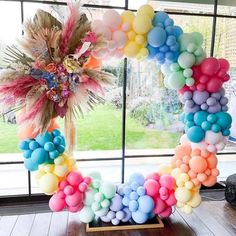 a wreath made out of balloons sitting on top of a wooden table next to a window