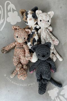 four crocheted teddy bears sitting next to each other on a gray tablecloth