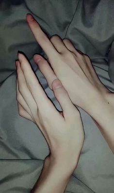 two hands touching each other on a bed