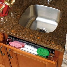 a stainless steel sink and counter top with wine glasses on the bottom, next to an empty dishwasher