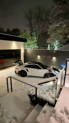 a white sports car parked in front of a house on a snowy day at night