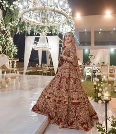 a woman in a red and gold bridal gown standing next to a chandelier