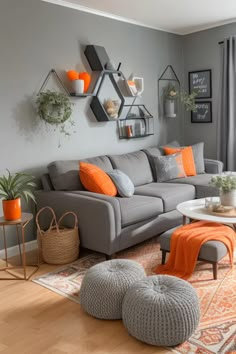 a living room with gray couches and orange accents on the walls, rugs and pillows