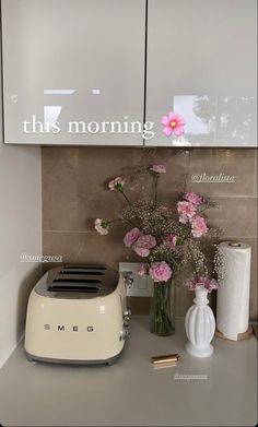 a white toaster sitting on top of a counter next to vases and flowers