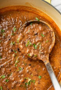 a ladle full of beans and meat in a sauce