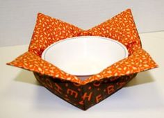 an origami bowl with orange and white designs on the inside is sitting on a table