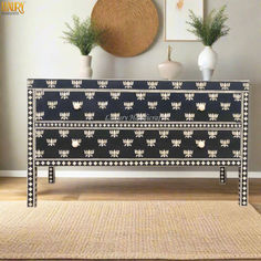 an ornate black and white dresser with two vases on it's sideboard